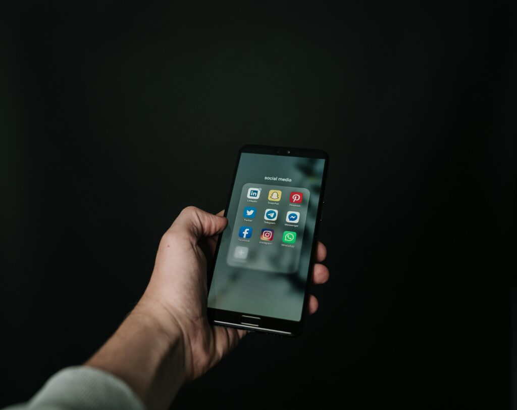 a hand holding a phone showing social media apps